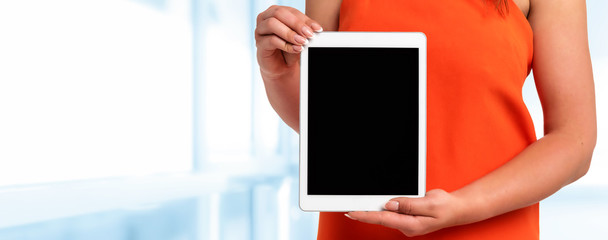 Canvas Print - Technology advertising banner - woman in orange dress with perfect fingernails holding digital tablet with blank screen (copy space).