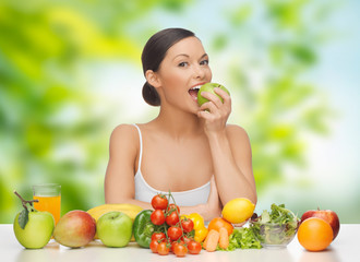 Sticker - diet, healthy food and people concept - woman eating green apple with vegetables and fruits on table over green natural background