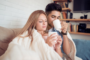 Sticker - Young couple relaxing on a sofa and drink coffee