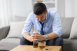 alcoholism, alcohol addiction and people concept - male alcoholic with bottle and drinking whiskey at home