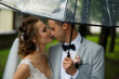© Wedding photography - Wedding rain. Bride and groom in the rainy weather are covered with a transparent umbrella and kisses. Selective focus on rain drops in umbrella