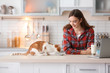 © Africa Studio - Beautiful young woman with cute cat in kitchen at home