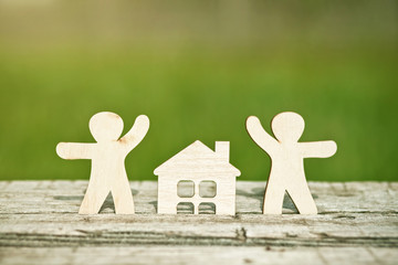 little wooden men and house on natural background. Symbol of construction, family, sweet home concept