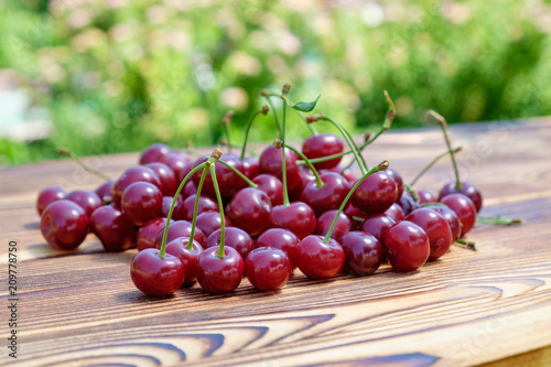 Fotografie, Obraz The heap of ripe red cherries on the wooden table on open air