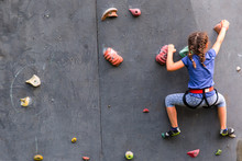 Beautiful Young Girl Climbing To Big Artificial Wall