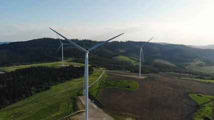 Wall Mural - aerial view of wind turbines rotate on ecological agricultural field under blue sunny sky with bright sunlight rasing on background windmill eco kinetic energy eco-business power of nature summer