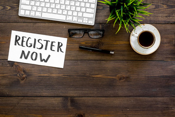 Poster - Membership concept. Template for registration. Register now hand lettering iconon word desk with glasses, coffee, plant on dark wooden background top view space for text