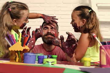 Wall Mural - children have fun with their father. Girls drawing on man face skin with colorful paints