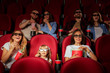 © fotofabrika - Group of friends sitting in movie theater with popcorn and drinks