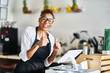 © Joshua Resnick - friendly shop assistant ready to take customer orders at register in restaurant