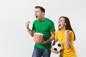 Wall Mural - European young couple, woman, man, football fans in yellow green t-shirt cheer up support team with soccer ball bucket of popcorn isolated on white background. Sport, family leisure, lifestyle concept