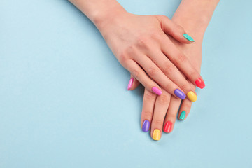 Hands with beautiful manicured nails. Girl hands with beautiful summer manicure on blue background in studio. Manicured hands and copy space.