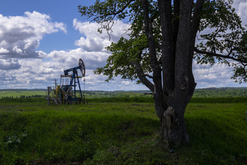 The beam pumping unit is homework, sunset in oil field. Oil pump oil rig energy industrial machine for petroleum. The pumping unit as the  pump installed on a well. Equipment of oil fields.