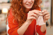Cheerful woman. Red-haired woman smiling broadly while feeling cheerful knitting nice pleasant presents