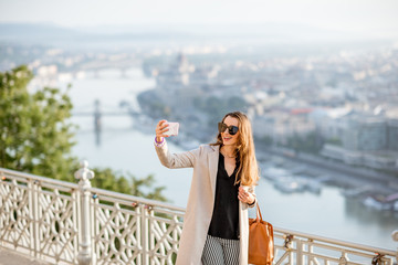 Wall Mural - Young woman making selfie photo on the beautiful cityscape background traveling in Budapest city, Hungary
