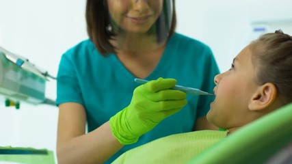 Wall Mural - Dentist examining little girl teeth, routine dental checkup in modern clinic