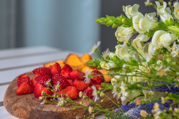 Breakfast, strawberry and peaches on a wooden surface with wildflowers. Copy space