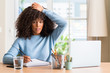 © Krakenimages.com - African american woman studying at home using a computer laptop stressed with hand on head, shocked with shame and surprise face, angry and frustrated. Fear and upset for mistake.