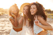 Picture of gorgeous young caucasian and african american women 20s in stylish clothing laughing and showing peace sign at camera, during summertime near ocean