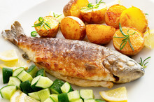 Fried Breaded Trout And Jacket Potato Decorated With Rosemary Served With Cucumber Salad And Lemon