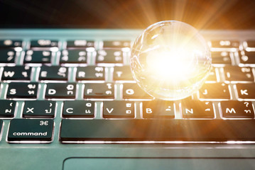 Wall Mural - Transparent global on laptop keyboard with sunlight in the middle. Business and technology concept.