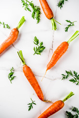 Wall Mural - Fresh raw carrots with green leaves, white marble background copy space top view