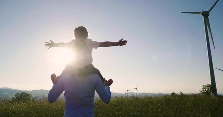 a father engineer holds his daughter in his arms and runs between the wind turbines with great freed