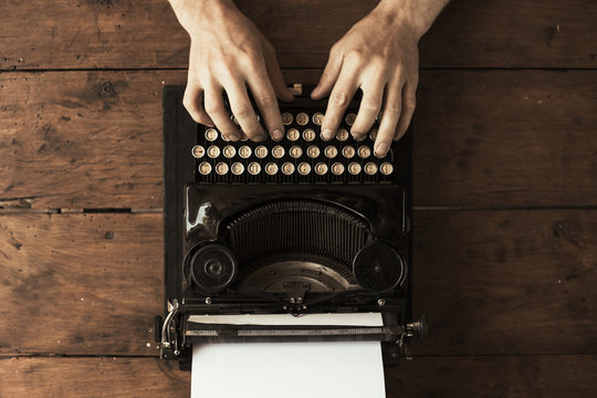 Young man's hands typing on an antique vintage typewriter