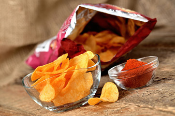 Hot chilli pepper potato crisps - chips and package of chips in background