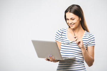 Wall Mural - Portrait of happy young beautiful surprised woman standing with laptop isolated on white background. Space for text.