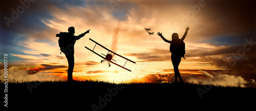 Fotografia couple looks at old biplanes fly at sunset