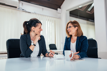 image of two business woman talking in bright office.