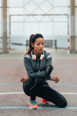 Wall Mural - Female urban athlete resting during outdoor workout. Fitness lifestyle and exercising concept. Sporty woman taking a training break.