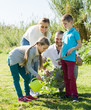 Parents with two kids planting a bush .
