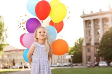 Cute little girl with colorful balloons outdoors on sunny day