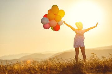 Wall Mural - happy woman with balloons at sunset in summer