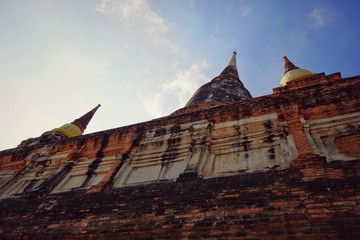 Travel Thailand - Pagoda and brick wall in Wat Yai Chaimongkol on blue sky and cloud background, Ayutthaya Historical Park. The brick pagoda at old ayutthaya temple ruins. Space for text in template.