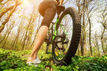 Wall Mural - Close-up of the foot of a woman cycling on the forest road. Woman feet riding mountain bike on outdoor trail on country grass road