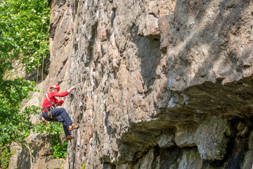 Rock climbing. A young climber climbs a vertical granite rock. Extreme sport.