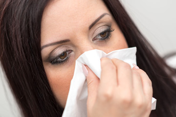 Portrait of woman blowing her nose, close up