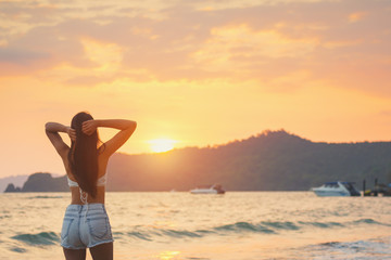 Wall Mural - Travel woman walking on beach in sunset