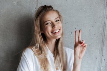 Wall Mural - Beautiful young woman indoors over grey wall