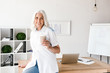 © Drobot Dean - Mature woman indoors in office working drinking coffee
