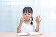 Leinwandbild Motiv Asian little Chinese Girl doing mathematics by counting fingers