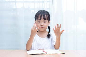 Asian little Chinese Girl doing mathematics by counting fingers