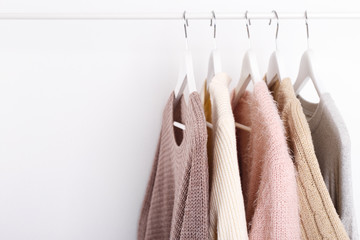 Warm knitted, autumn, winter clothes hanging on a rack, trending concept, pastel colors