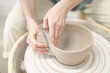 Woman hands makes clay pot on the pottery wheel