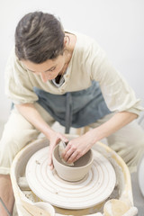 Woman hands makes clay pot on the pottery wheel