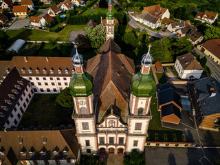 Wall Mural - Soaring majestic church Saint Maurice in little french village Ebersmunster. Aerial drone view.