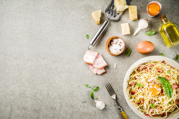 Wall Mural - Traditional italian pasta, spaghetti carbonara with bacon, creamy sauce, parmesan cheese, egg yolk and fresh basil leaves grey stone background copy space